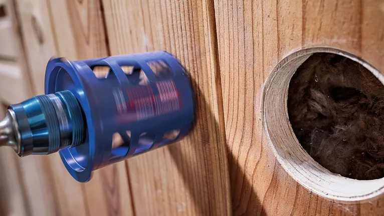 Perçage d'une grande ouverture circulaire à la scie cloche dans un mur en bois.